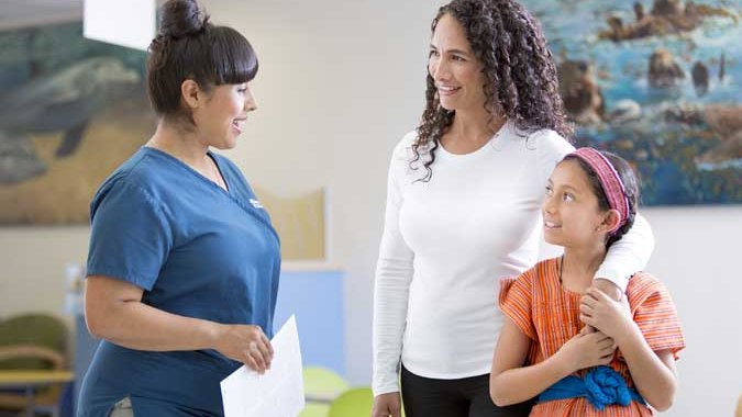 Stanford Medicine Children’s Health clinician with a parent and her child.	Médica de Stanford Medicine Children's Health con una madre y su hija.