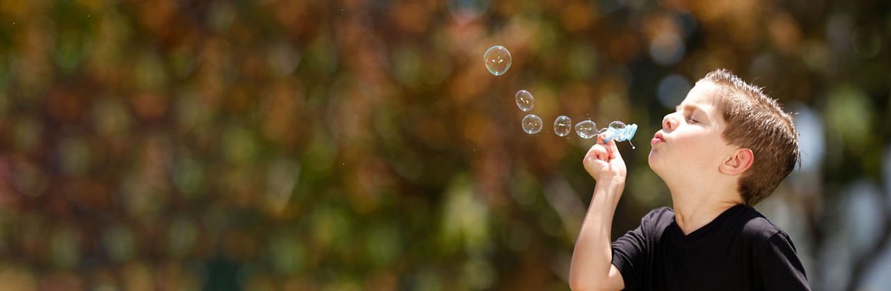 A young boy, from Stanford Medicine Children's Health Aerodigestive Program, blowing bubbles at Lucile Packard Children's Hospital Stanford