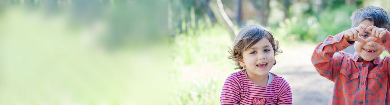 Niña y niño sonriendo afuera