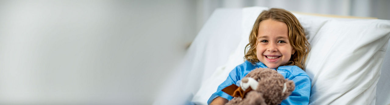 Child smiling holding a stuffed bear