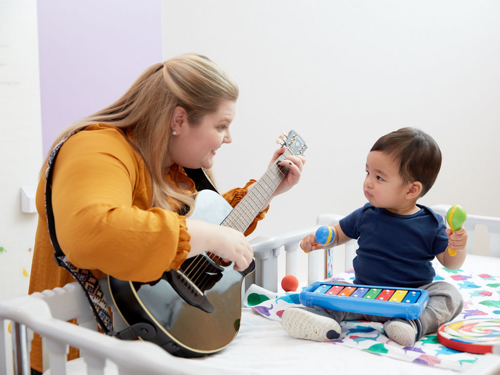 Music Therapist playing the guitar to a young boy at Lucile Packard Children's Hospital Stanford in Palo Alto, California