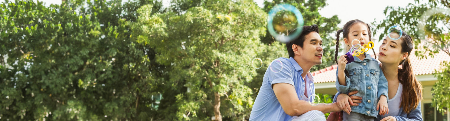 Parents and child blowing bubbles outside