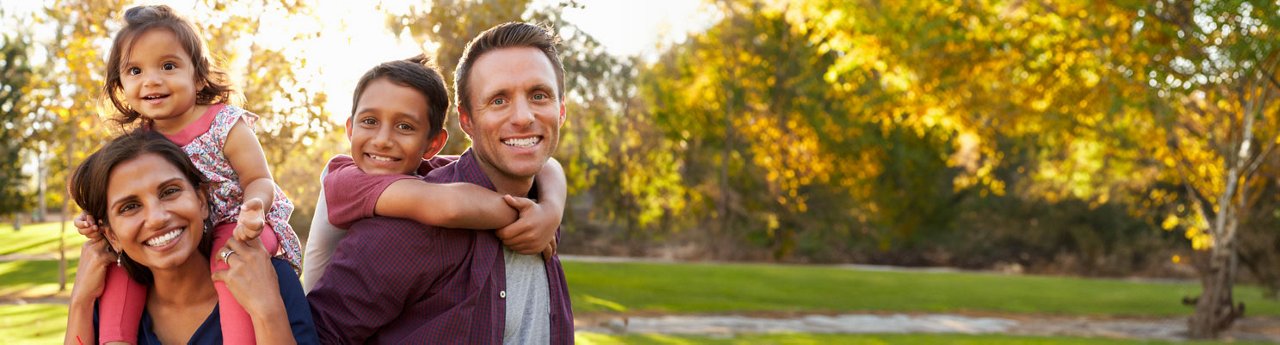 parents carry their kids on piggyback in the park