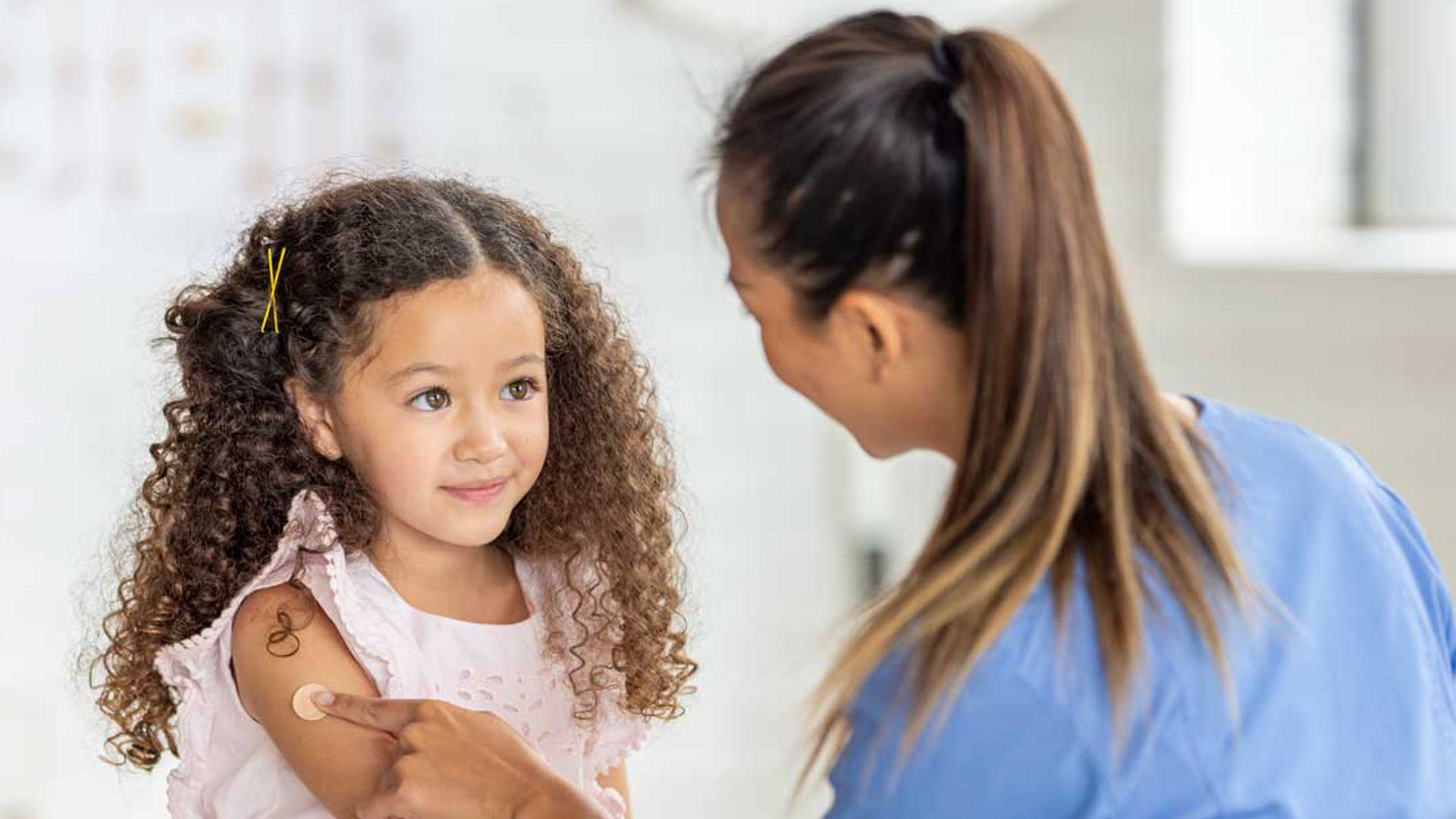 Young girl with a clinican getting a band-aid for her flu shot