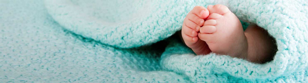 baby feet wrapped in a fuzzy blue blanket