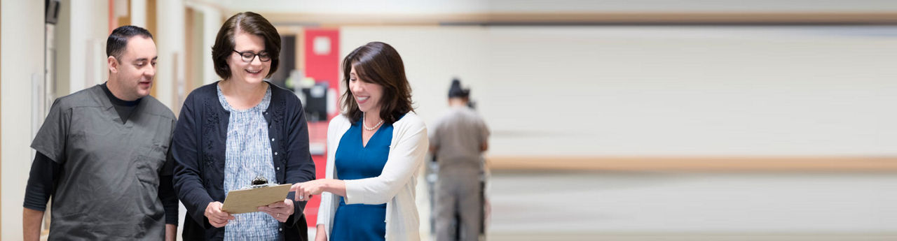 Health professionals smiling at clipboard while standing in hallway