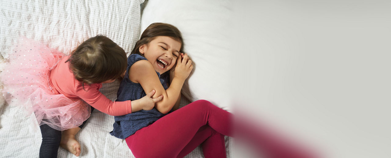 Dos niños pequeños jugando en una cama