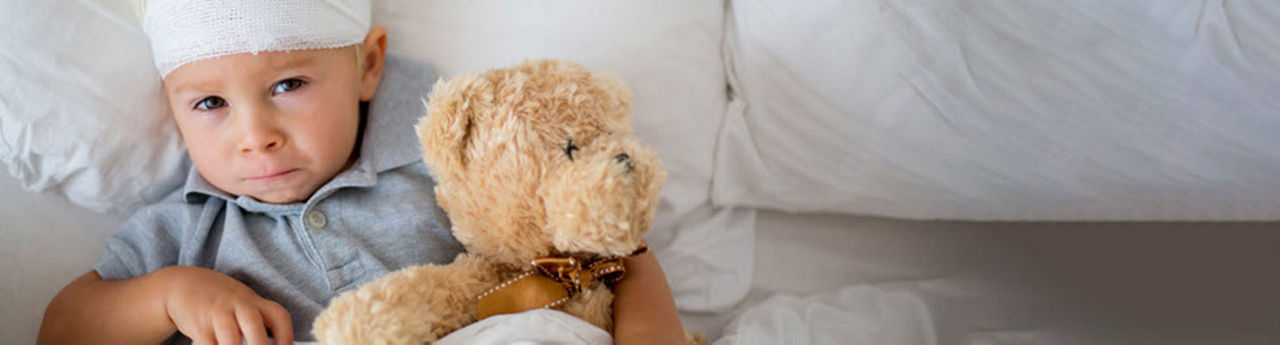 Niño en una cama de hospital con un peluche