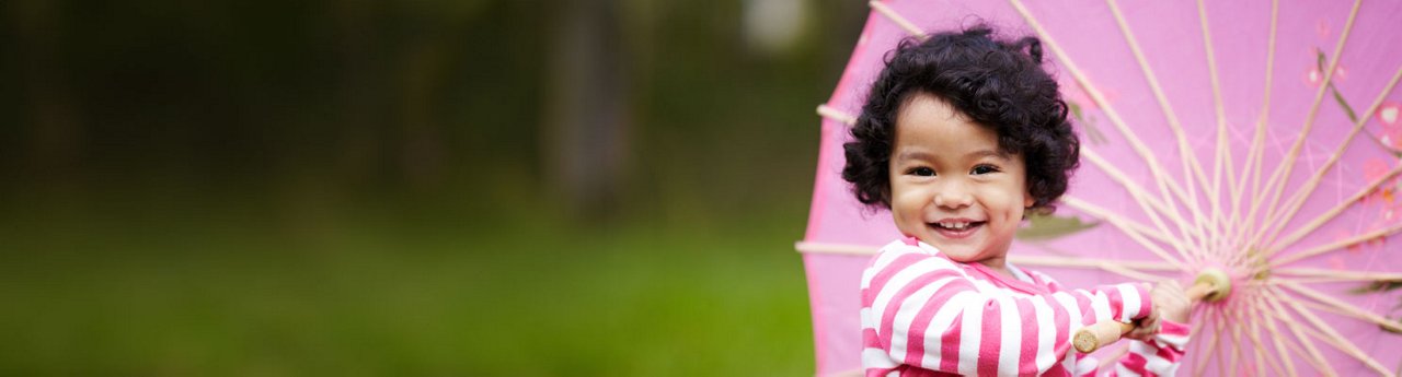 Young girl twirling a pink umbrella