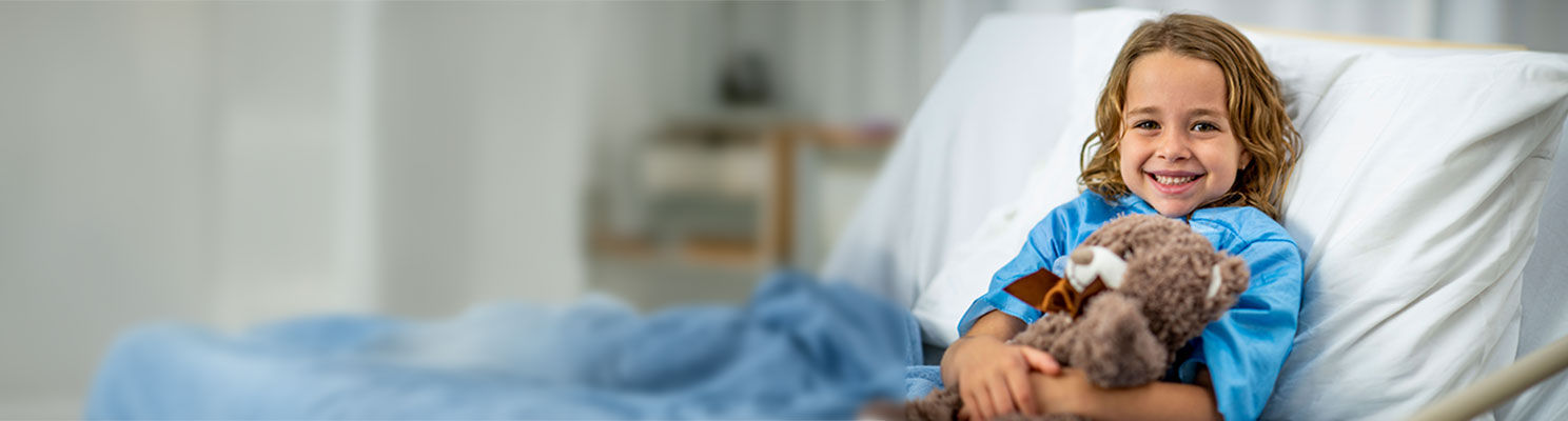 little girl in hospital bed with teddy bear