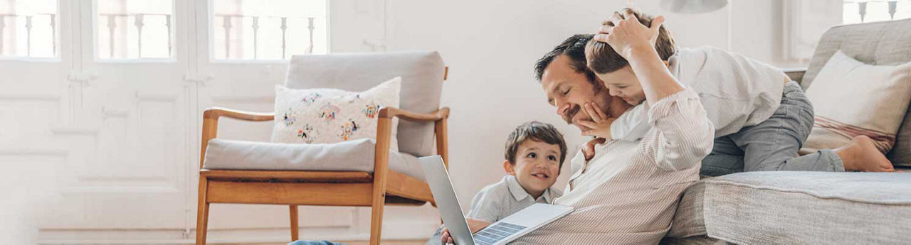 Padre mirando su computadora con sus hijos