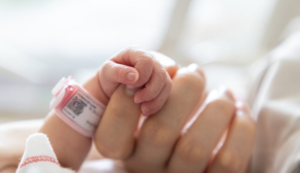 Baby hand squeezing adult hand