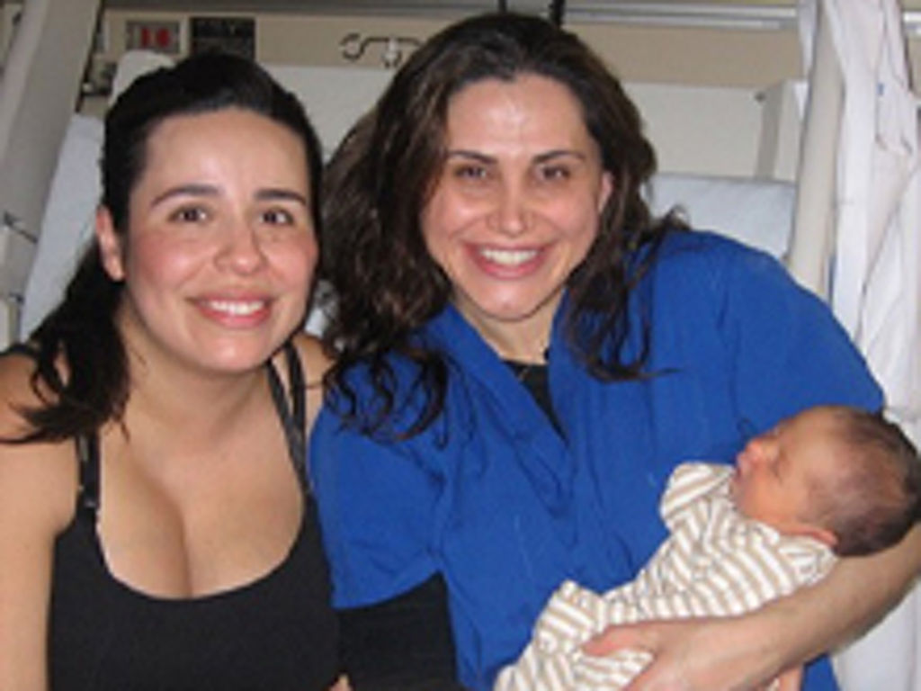 Dr. Natali Aziz holding baby and sitting next to mother