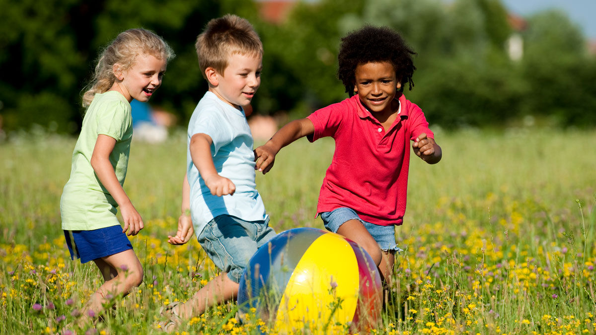 children running in a field with a big ball