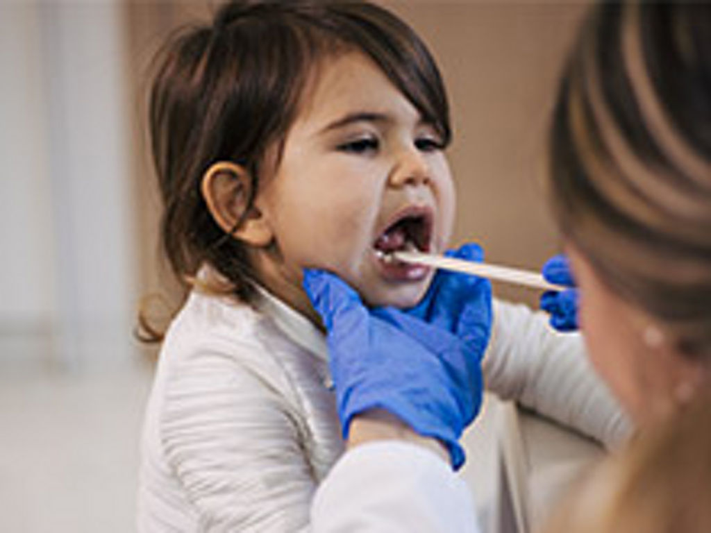 Pediatrician checking child's tonsils